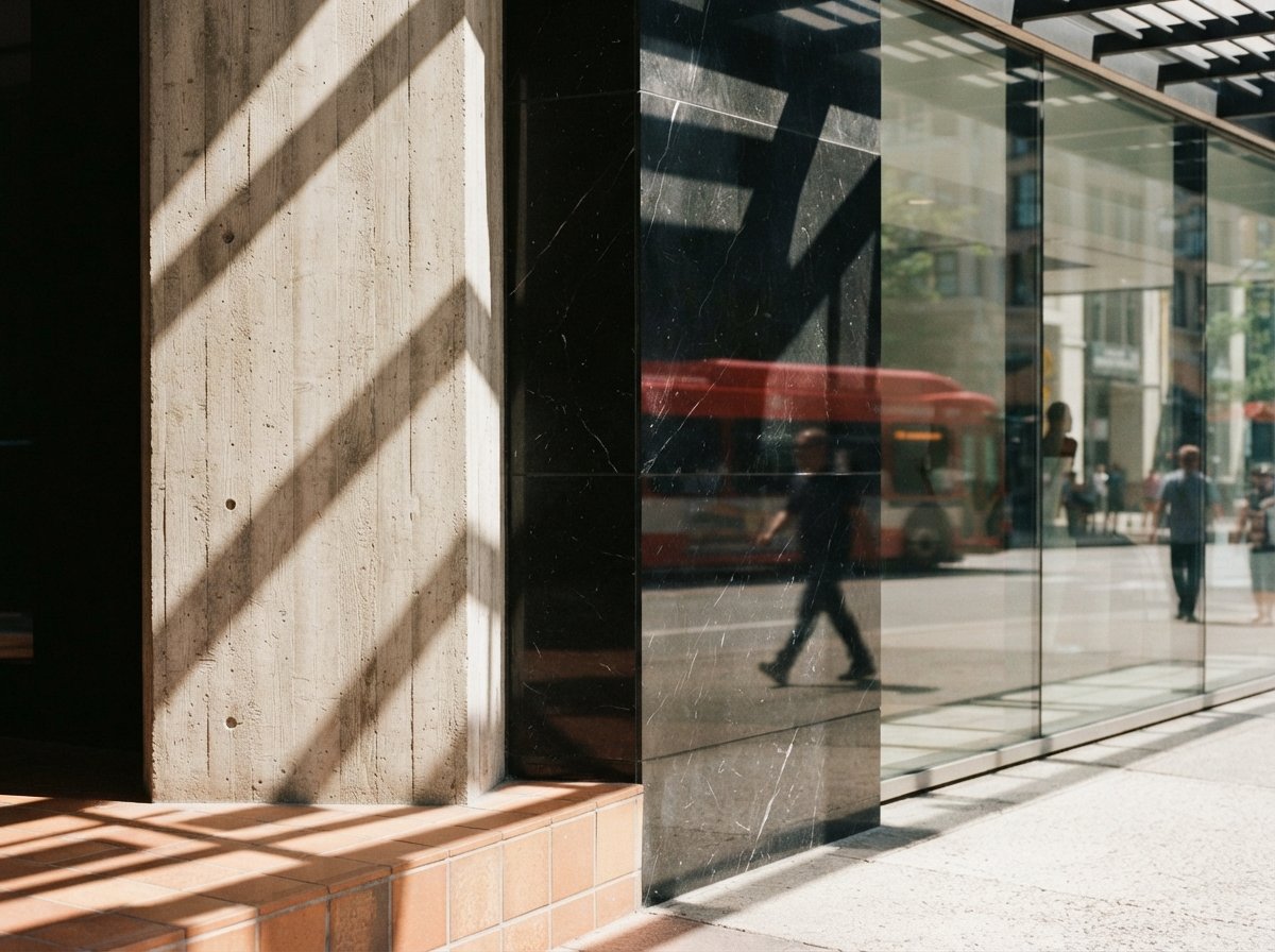 A close-up photograph displays geometric shadows casting across concrete, terracotta tile, and mirrored black marble.