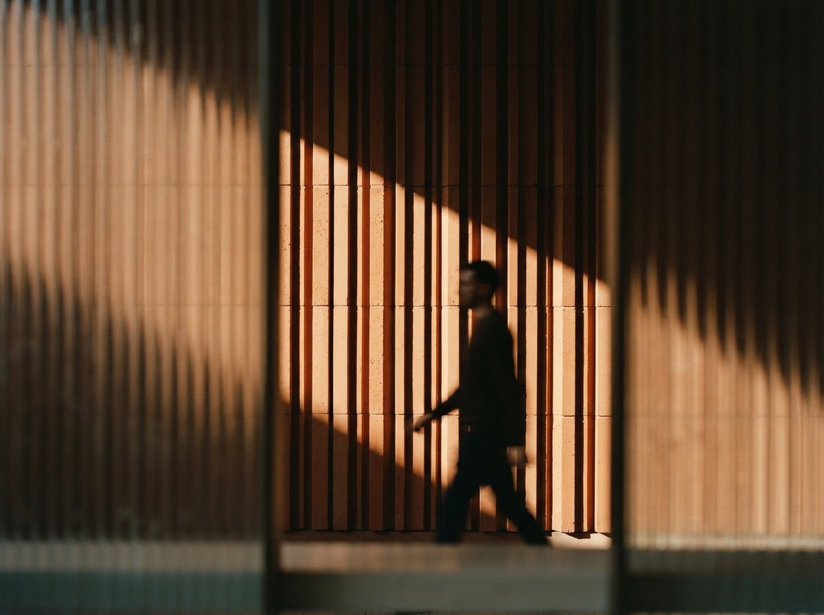 A close-up macro view of textured terracotta facade louvers casting crisp diagonal shadows.